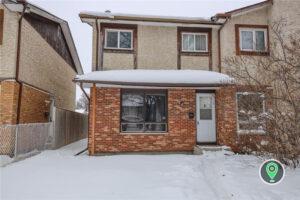 a house covered in snow in front of a brick building